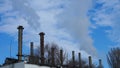 Huge metal pipes of the plant release white smoke or steam into the atmosphere