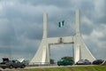 Huge metallic gate-sign holding Nigerian flag in green and white at national highway at the entrance to capitol city of Nigeria, A