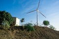 Huge modern windmill on hills with buildings in front and blue sky behind Royalty Free Stock Photo