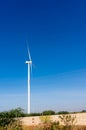 Huge modern windmill on hills with buildings in front and blue sky behind Royalty Free Stock Photo