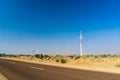 Huge modern windmill on hills with buildings in front and blue sky behind. Royalty Free Stock Photo