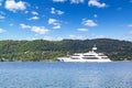 Huge motor yacht sailing in the sea near island with green mountains, sunny day with clouds, blue sky in Greece