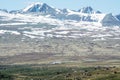 Huge mountain scenery with wooden cabins used as sense of scale.