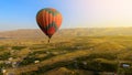 Huge multicolored hot air balloon flying over Armenian village, landscape