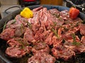 Huge pan with raw meat like ribs and steaks with spices and vegetables ready prepared for cooking