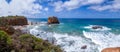 A huge panorama on a blue bay with a precipitous shore on a sandy beach, jutting out of the water by rocks washed by the ocean Royalty Free Stock Photo