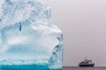 Huge piece of iceberg with antarctic cruise ship at the horizon, Antarctica Royalty Free Stock Photo