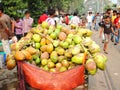 A huge pile of coconuts being sold at a busy market area