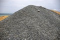 Huge pile of grey gravel on coast. Construction site material. Big gravel heap outdoor. Construction supply closeup.