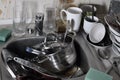 A huge pile of unwashed dishes in the kitchen sink and on the countertop. A lot of utensils and kitchen appliances before washing Royalty Free Stock Photo