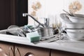 A huge pile of unwashed dishes in the kitchen sink and on the countertop. A lot of utensils and kitchen appliances before washing Royalty Free Stock Photo