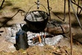 Huge pot of liquid food heating in a large pot at a campsite fire