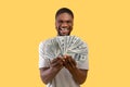 Huge profit concept. Wealthy black man with lots of money excited over his big success over yellow background