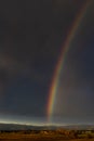 Huge rainbow over the Tuscan countryside against a dark cloudy sky, Bientina, Pisa, Italy