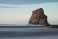 Huge rock cliff isolated in ocean in long exposure in sunset sky, hendaye, basque country, france