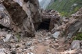 huge rock slide, blocking entrance to mountain cave, with dust and debris still settling