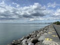 Huge rocks line a concrete breakwater wall along the seaside park under dark clouds. Royalty Free Stock Photo