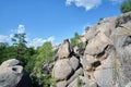 Huge rocky boulder formations high in mountains with growing trees on summer sunny day