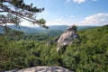 Huge rocky boulder formations high in mountains with growing trees on summer sunny day