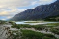 A huge rocky mountain range in the valley of the Akkol river in Altai, with a river and a clay bank with grass, with beautiful Royalty Free Stock Photo