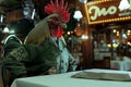 A huge rooster in an old green, filthy tennis suit sits at a table in a restaurant, AI generated