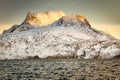 Huge Sermitsiaq mountain in a sunset rays covered in snow with blue sea and small fishing boat, nearby Nuuk city, Greenland