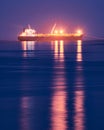 Huge ship at the sea at night with the lights reflecting on the water