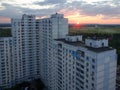 A huge skyscraper of non-standard design with different number of floors in the evening. Behind him, the sun is setting in the