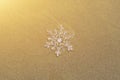 Huge sparkling snowflake on the sand in the sea foam. Concept of Winter and Christmas vacation on the beach Royalty Free Stock Photo