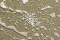 Huge sparkling snowflake on the sand in the sea foam. Concept of Winter and Christmas vacation on the beach Royalty Free Stock Photo