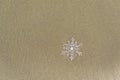 Huge sparkling snowflake on the sand in the sea foam. Concept of Winter and Christmas vacation on the beach and resort. Royalty Free Stock Photo