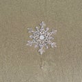 Huge sparkling snowflake on the sand in the sea foam. Concept of Winter and Christmas vacation on the beach Royalty Free Stock Photo