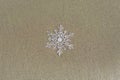 Huge sparkling snowflake on the sand in the sea foam. Concept of Winter and Christmas vacation on the beach Royalty Free Stock Photo