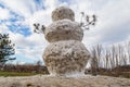 Huge spring snowman in melted meadow. Background with copy space for lettering or text Royalty Free Stock Photo