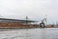 Huge stacks of tree trunks lie in a transshipment port and are loaded by a large crane