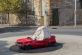 Huge stone dropped on red car as outdoor sculpture at Pottinger