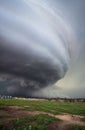 A huge supercell storm with a ground scraping wall cloud fills the sky over Nebraska farmland.