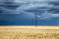 Huge thundercloud over a wheat field and electric pylons Royalty Free Stock Photo