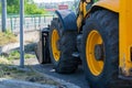 Huge tractor wheels, grader on the side of the city street