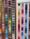 A huge wall, collection full of cotton reels, lots of colorful horizontal spools of thread on display at the notions store