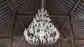 A huge white Chandelier weighs under a dark roof. Royalty Free Stock Photo