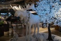 Huge white statue of moose with necklace from big mirrored silver Christmas balls. Creative New Year decorations with moose statue