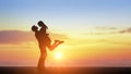 Couple kissing with beautiful sunset in background, man lifting woman. Couple in love silhouette during sunset, backlit. copy Royalty Free Stock Photo