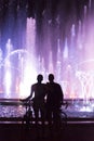 Hugging couple watching color fountain show at night