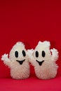 Hugging funny ghosts decoration against red background and consistent copy space