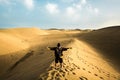 Hugging the power and feeling of nature for lonely man doing trekking in the desert dunes with ocean at the end. yellow and blue