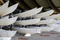 Hulls of school sailboats racked one above another on two levels in a dry rack boat storage facility in winter season