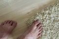 Human bare feet standing on the floor. One foot on carpet and an Royalty Free Stock Photo