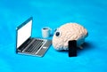 Human brain figurine working on a laptop