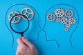 Human brain is made gear mechanism on blue background. The brain is viewed through a magnifying glass. Two different thought Royalty Free Stock Photo